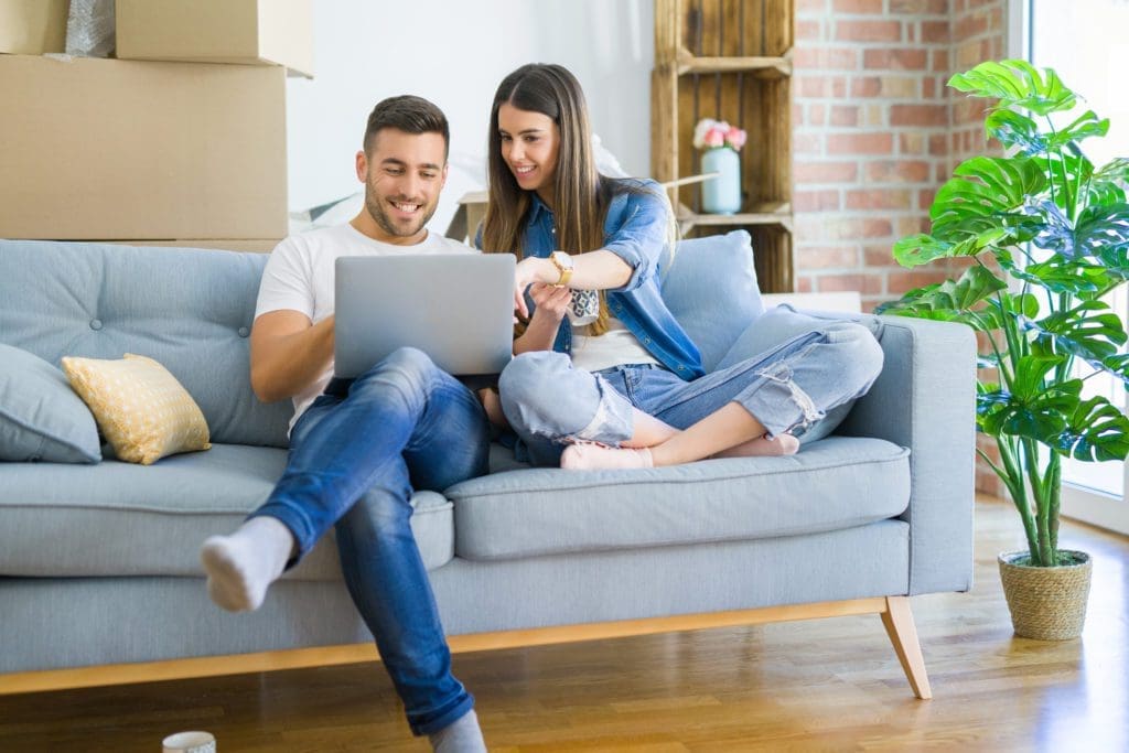 Young couple moving to a new home relaxing sitting on the sofa u